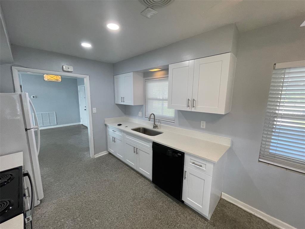 A kitchen features white cabinets, light countertops, a black dishwasher, and grey walls — 520 SENECA TRAIL, MAITLAND, FL
