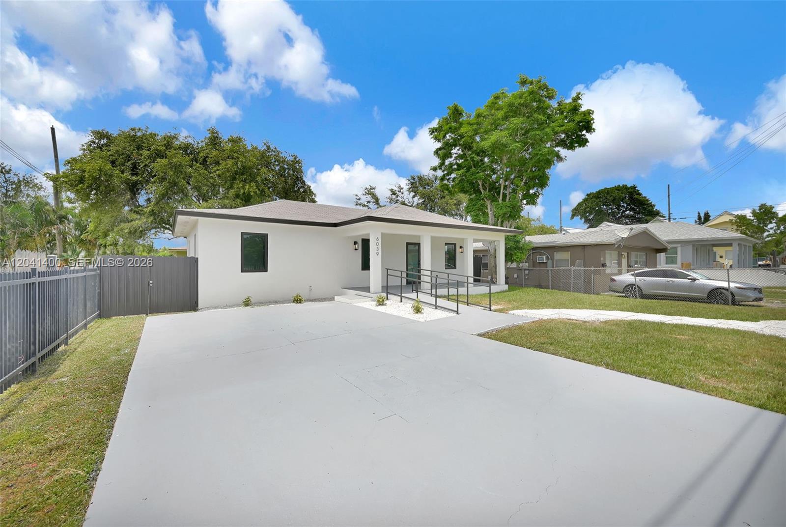 A single-story white house features a concrete driveway, a front porch, and a metal ramp — 6039 SW 63rd Ter, South Miami FL 33143, SOUTH MIAMI, FL