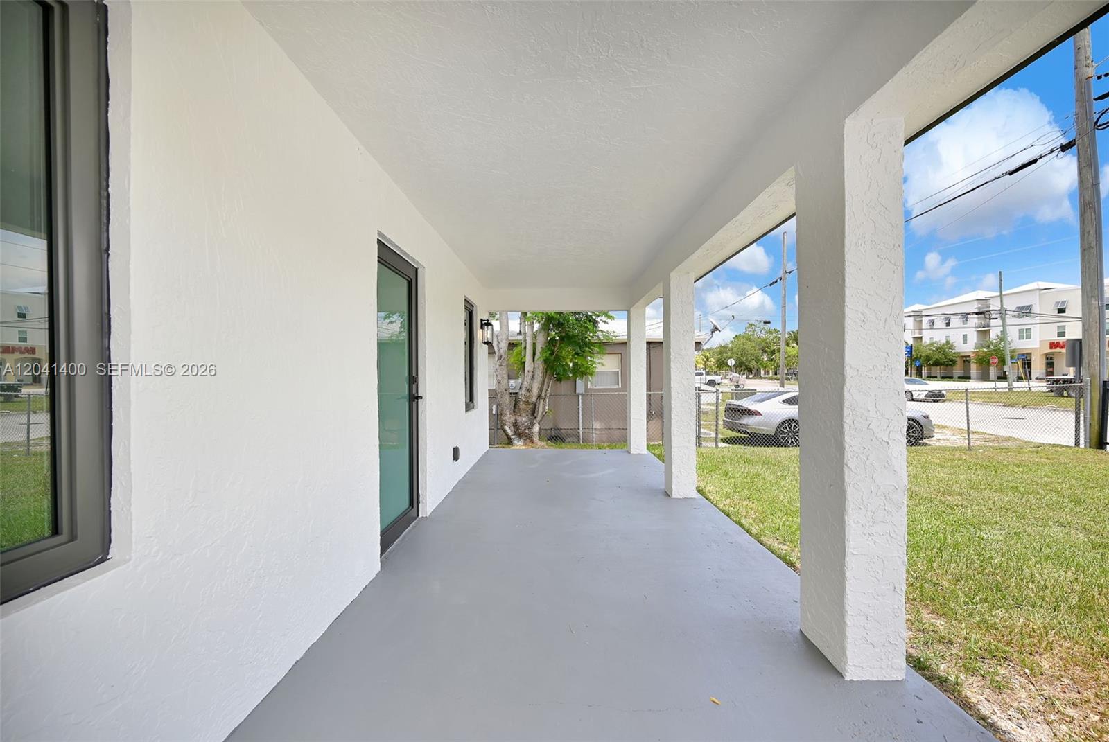 A covered porch with a gray floor, white stucco walls, and square support columns — 6039 SW 63rd Ter, South Miami FL 33143, SOUTH MIAMI, FL