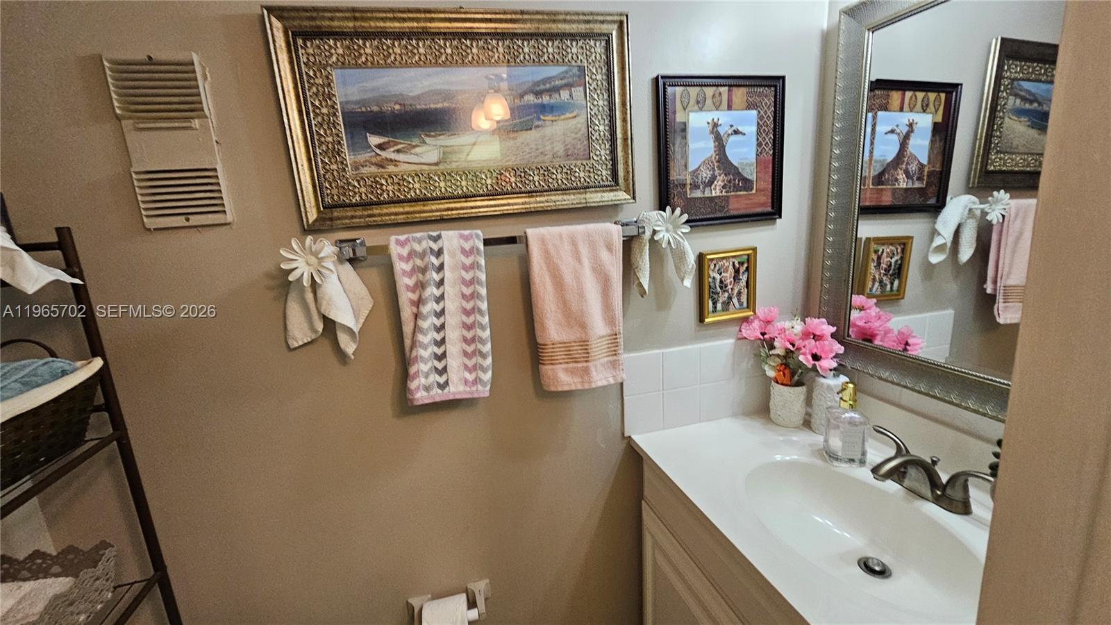 A bathroom features a vanity with a white sink, a towel rack, and wall art — 4980 E Sabal Palm Blvd # 132, Tamarac FL 33319, TAMARAC, FL