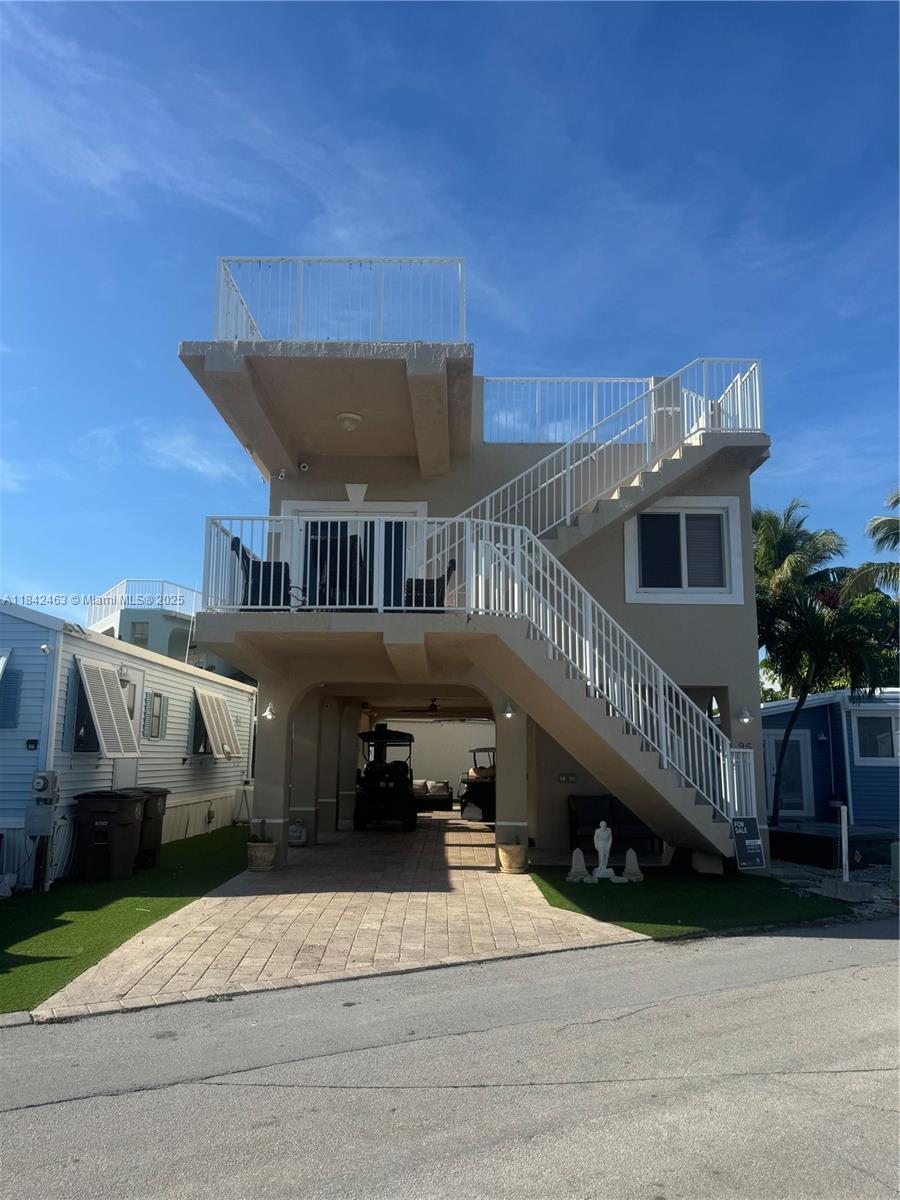 An elevated two-story house features an open ground-level carport, an exterior staircase, and a rooftop deck — 65821 Overseas Hwy, Long Key FL 33001, LONG KEY, FL