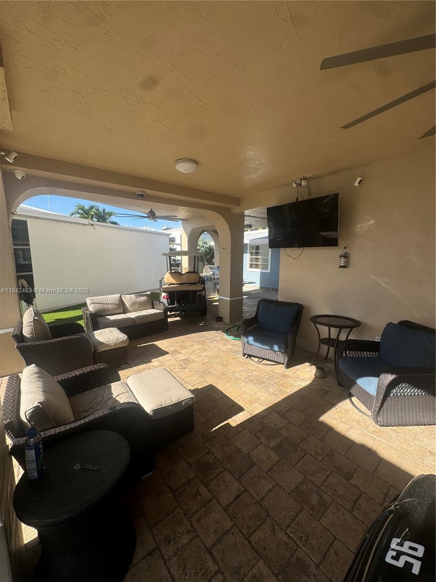 A covered outdoor patio features stone pavers, wicker furniture, a mounted television, and a golf cart — 65821 Overseas Hwy, Long Key FL 33001, LONG KEY, FL