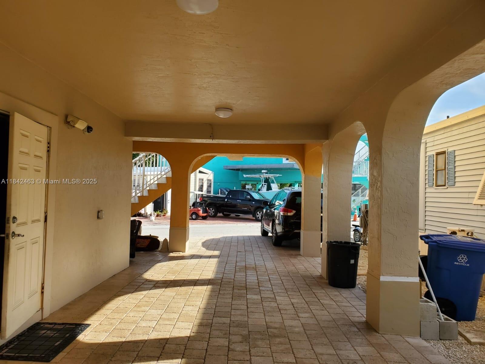 A covered carport with paved flooring, arched support columns, and a white door — 65821 Overseas Hwy, Long Key FL 33001, LONG KEY, FL