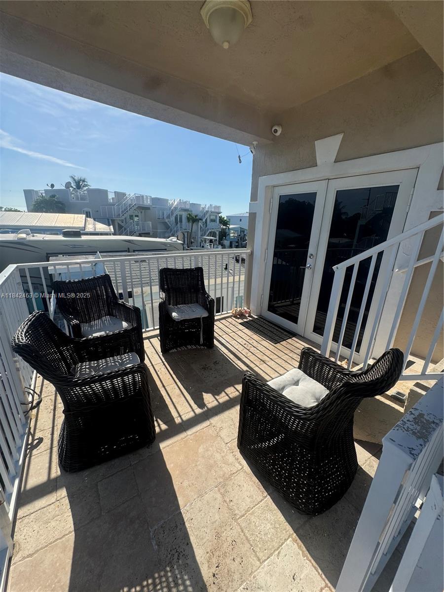 A balcony features four black wicker chairs with cushions on a tiled floor — 65821 Overseas Hwy, Long Key FL 33001, LONG KEY, FL