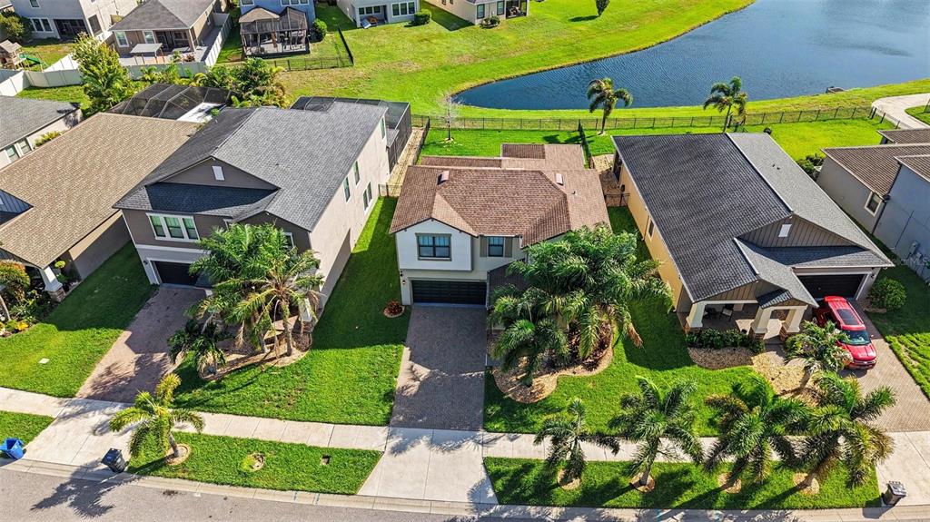 An aerial view of three suburban houses with palm trees and a nearby pond — 10032 SAGE CREEK DRIVE, SUN CITY CENTER, FL