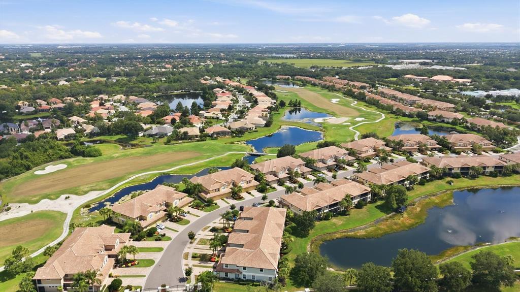 An aerial view shows a residential community with multi-family buildings, ponds, and a golf course — 8434 MIRAMAR WAY, LAKEWOOD RANCH, FL