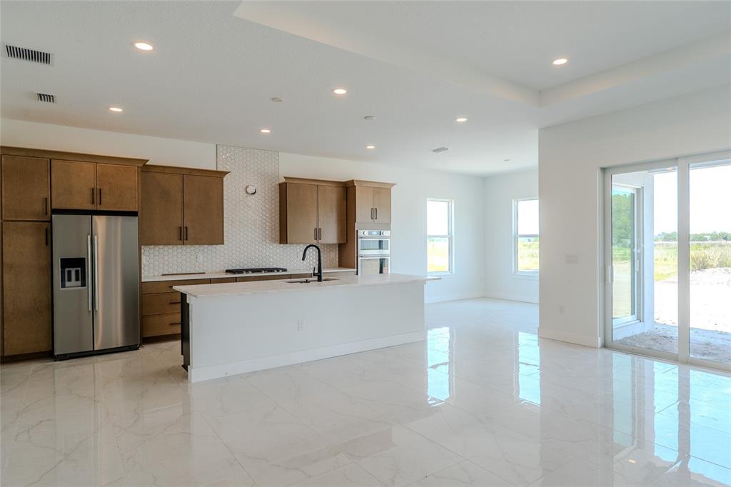 A modern kitchen features wood cabinets, a white island, and light tile flooring — 659 MALDIVES TRAIL, SARASOTA, FL