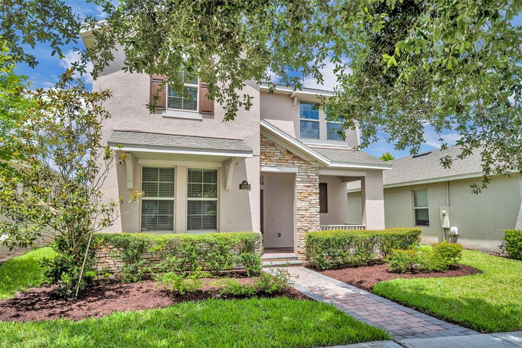 A two-story house with a stone-accented facade, a brick walkway, and a landscaped front yard — 8220 BAYVIEW CROSSING DRIVE, WINTER GARDEN, FL