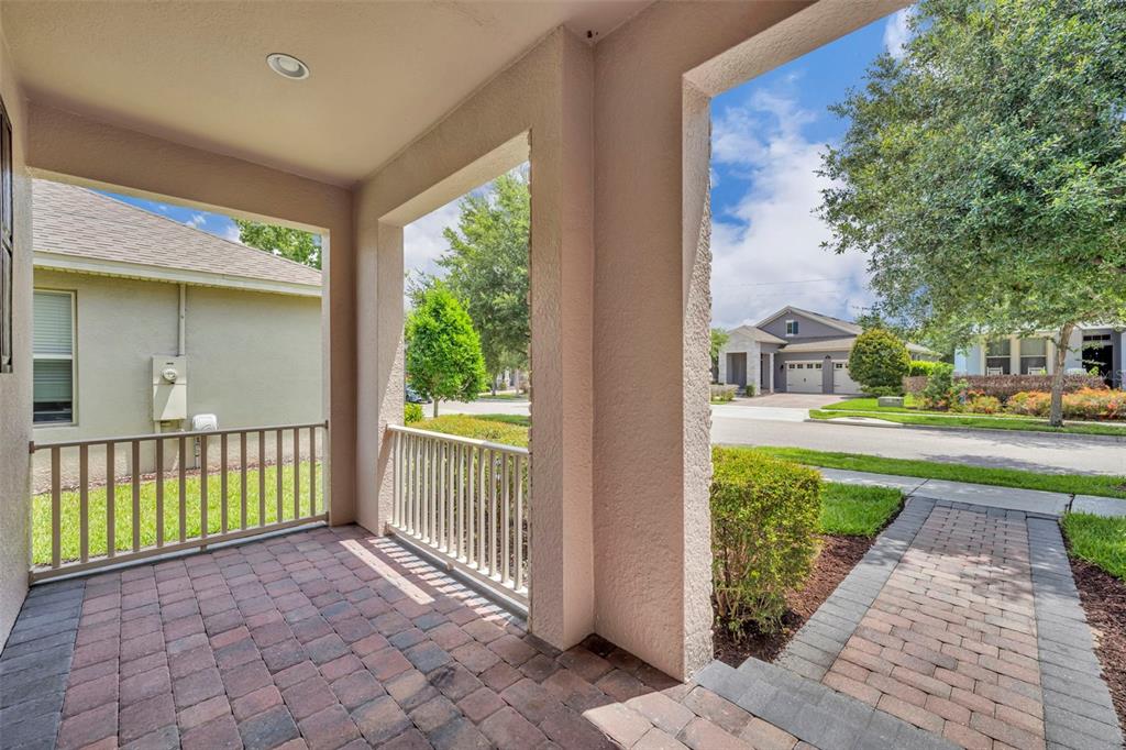 A covered front porch with brick pavers and a white railing overlooks a suburban street — 8220 BAYVIEW CROSSING DRIVE, WINTER GARDEN, FL