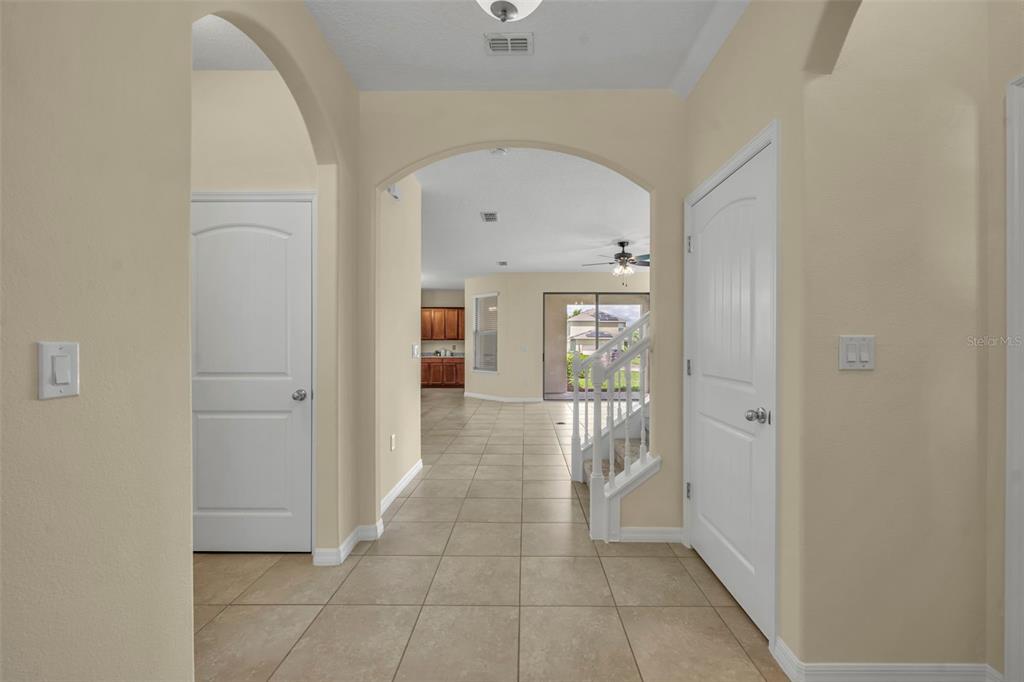 A tiled entryway leads to an open living area with a staircase and arched doorways — 8220 BAYVIEW CROSSING DRIVE, WINTER GARDEN, FL