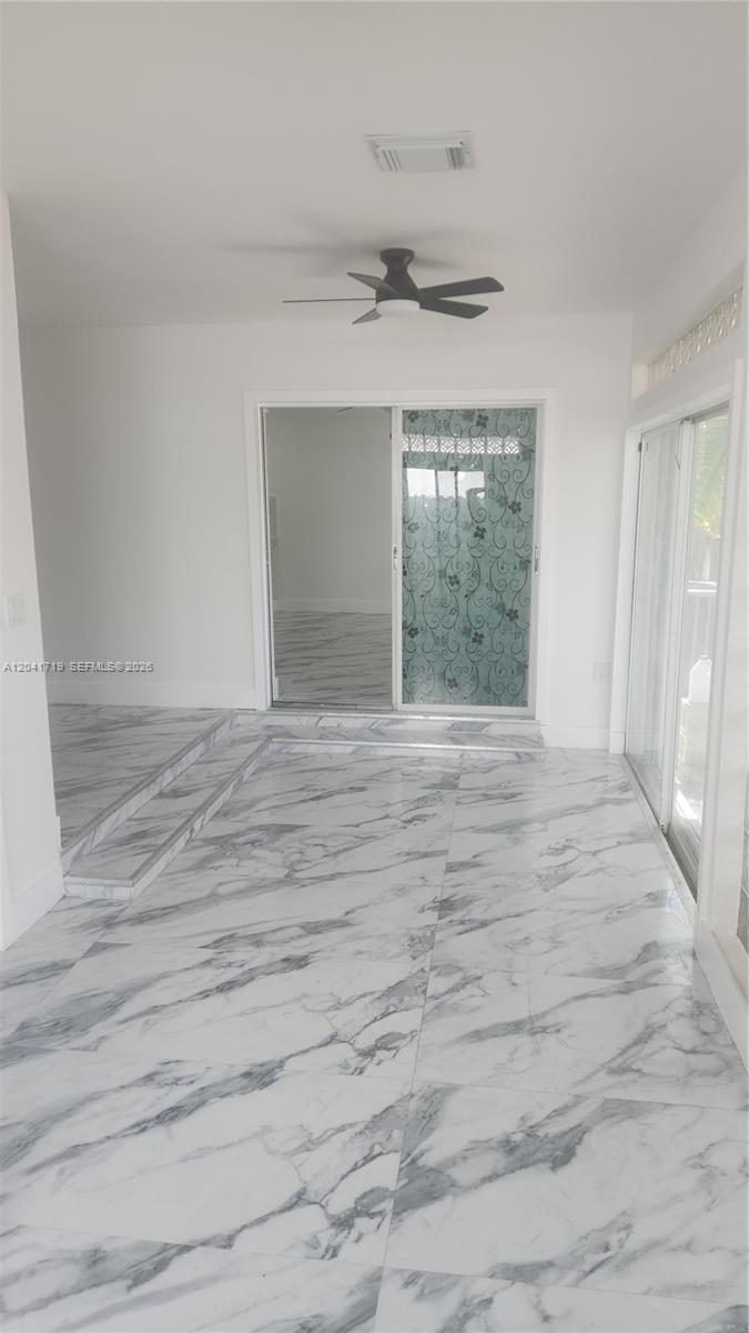 A modern kitchen features white cabinets, stainless steel appliances, and white marble-patterned countertops and flooring — 11491 SW 72nd Ter, Miami FL 33173, MIAMI, FL