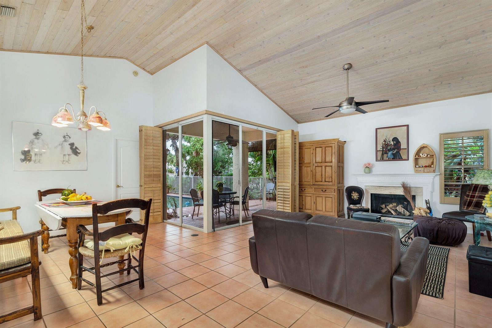 A living and dining area with vaulted wood ceilings, tile floors, and a fireplace — 9358 Heathridge Drive, West Palm Beach FL 33411, WEST PALM BEACH, FL