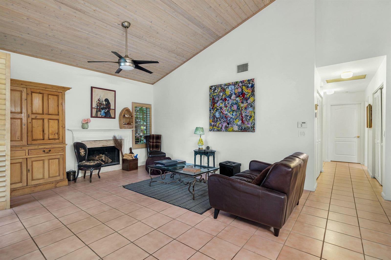 A living room features a fireplace, vaulted wood-paneled ceiling, tile flooring, and a leather sofa — 9358 Heathridge Drive, West Palm Beach FL 33411, WEST PALM BEACH, FL