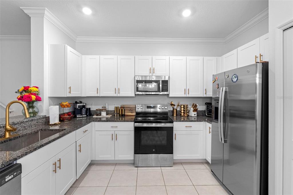 A kitchen features white cabinets, stainless steel appliances, and granite countertops — 36488 WELL HILL WAY, ZEPHYRHILLS, FL