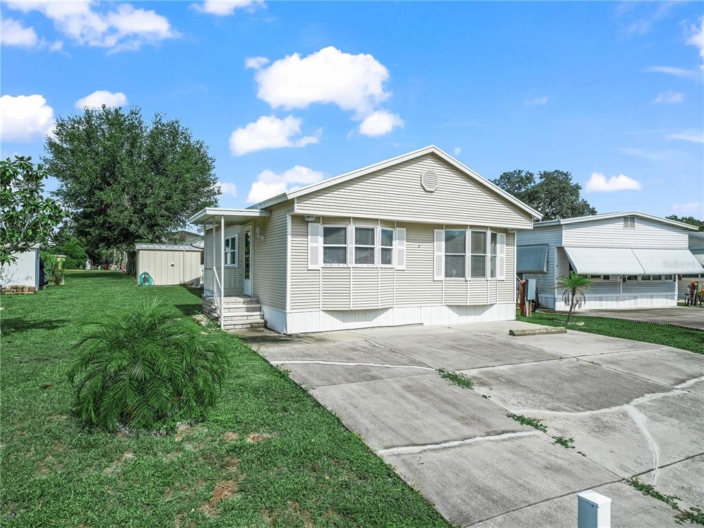 A light-colored manufactured home with a concrete driveway and a small front yard — 108 SILVERSIDES STREET, LAKE WALES, FL