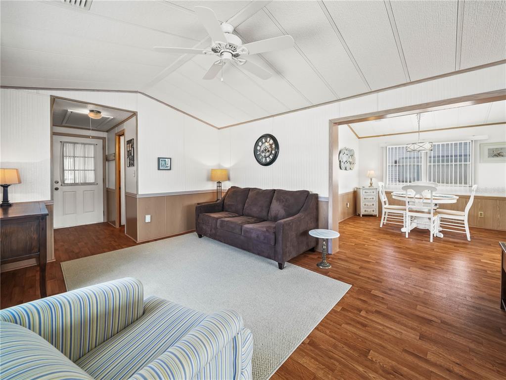 A living room with wood-look flooring, a brown sofa, and an adjacent dining area — 108 SILVERSIDES STREET, LAKE WALES, FL
