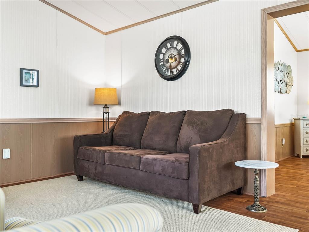 A living room features a brown sofa, a wall clock, and a floor lamp — 108 SILVERSIDES STREET, LAKE WALES, FL