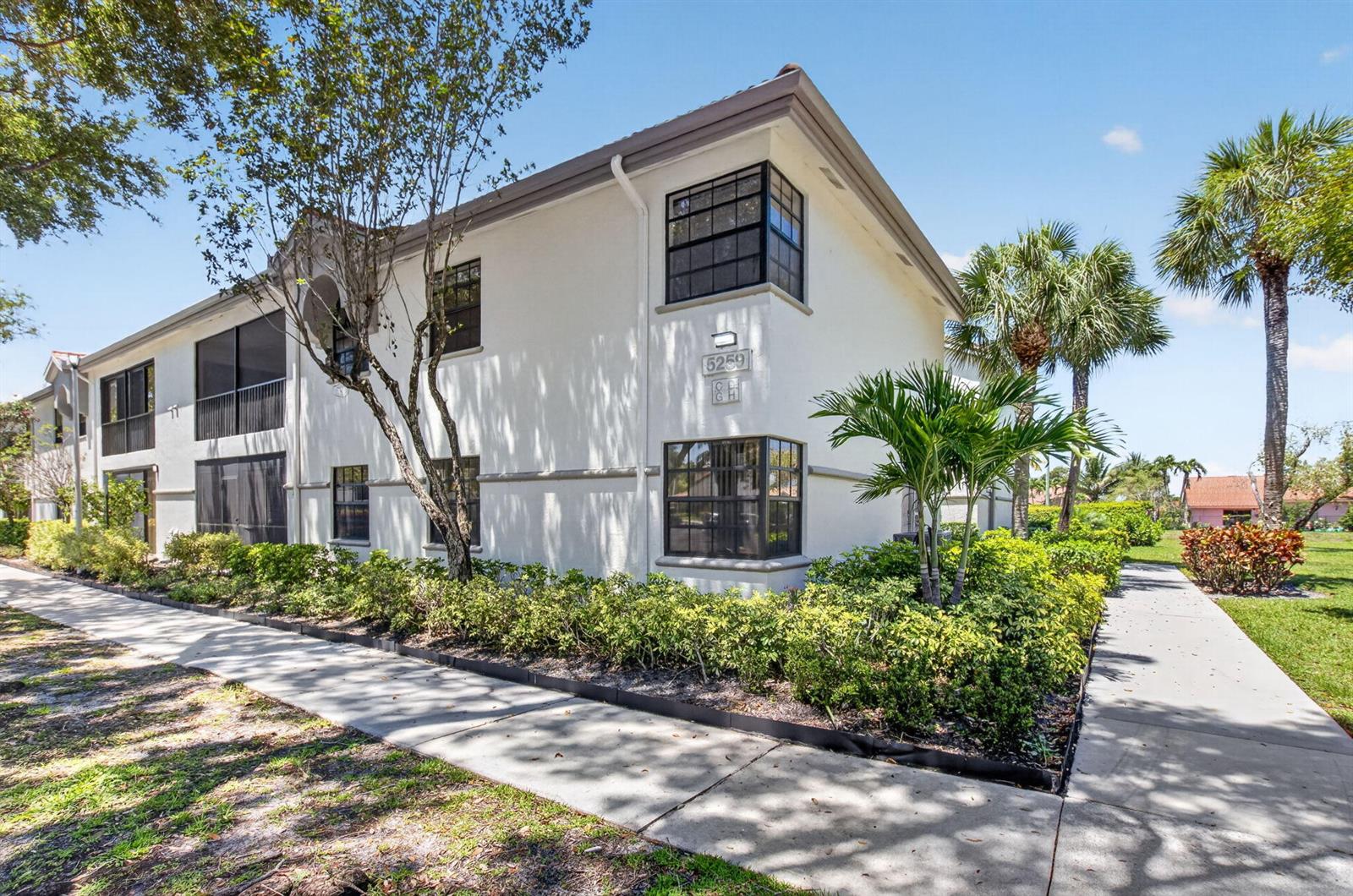 A two-story white stucco apartment building features black-framed windows and a sidewalk in front — 5259 Europa Drive # D, Boynton Beach FL 33437, BOYNTON BEACH, FL