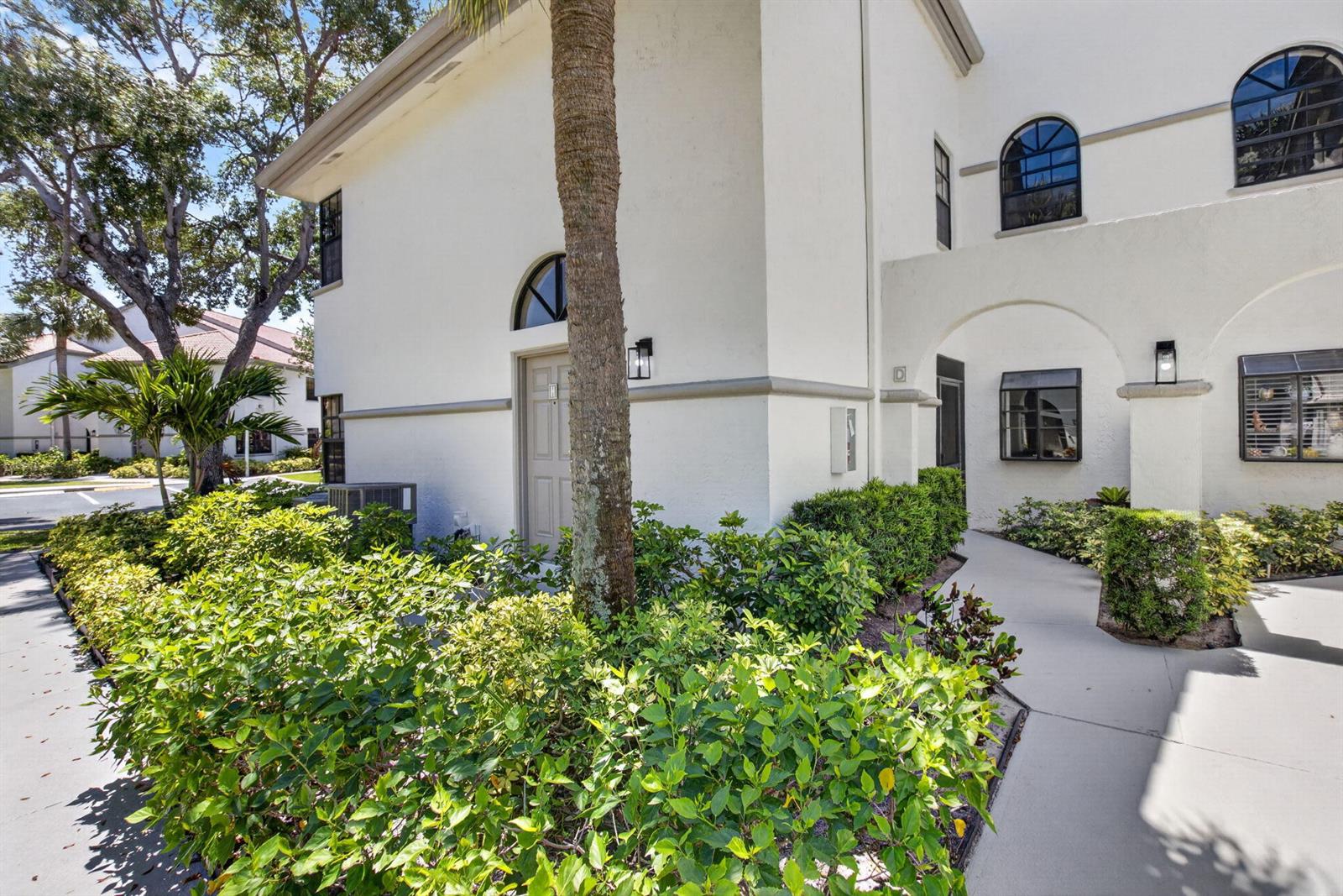 A white two-story building exterior features arched windows, a palm tree, and a concrete walkway — 5259 Europa Drive # D, Boynton Beach FL 33437, BOYNTON BEACH, FL