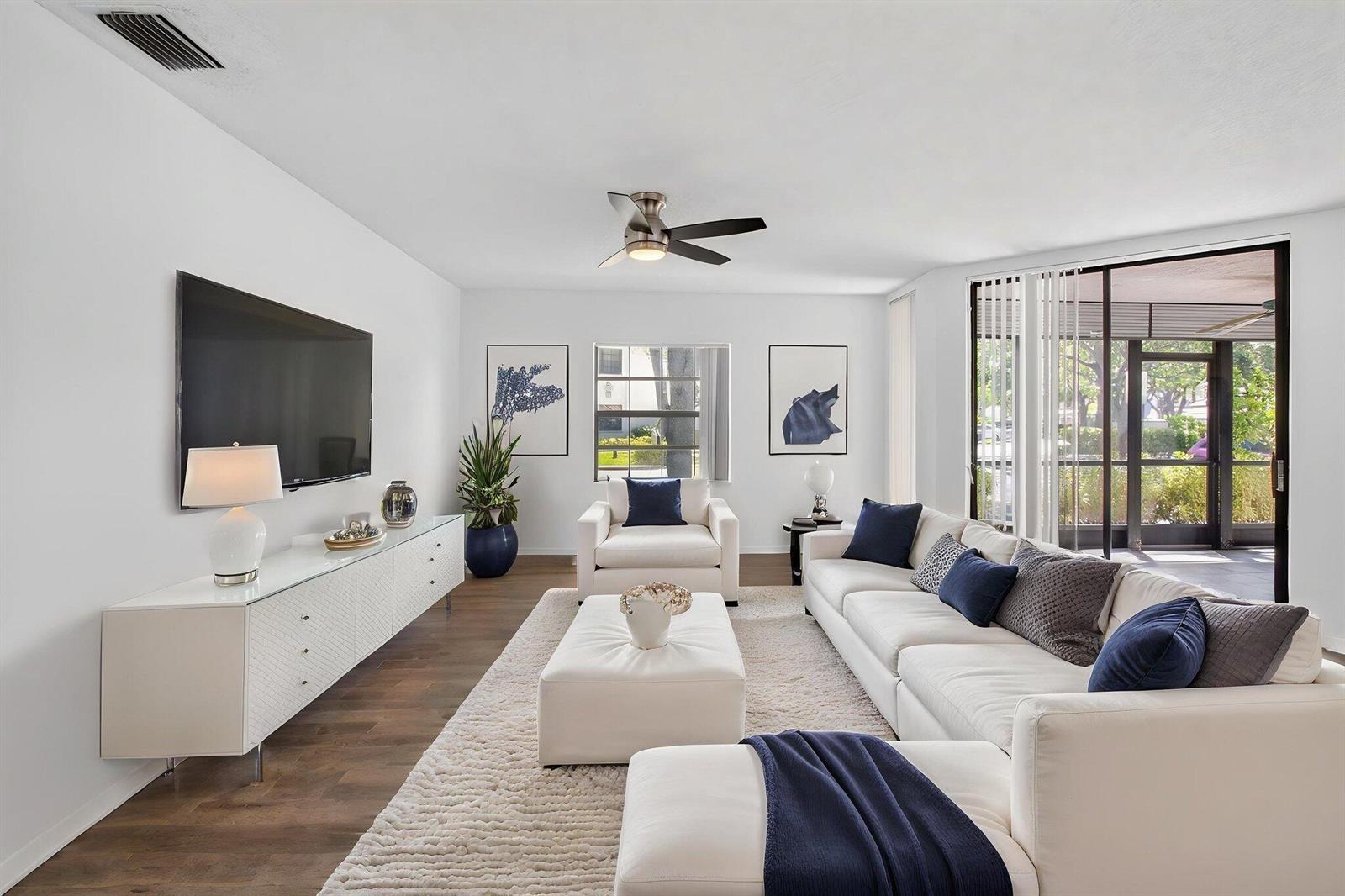 A bright living room features white furniture, a large sectional, and a glass-topped media console — 5259 Europa Drive # D, Boynton Beach FL 33437, BOYNTON BEACH, FL