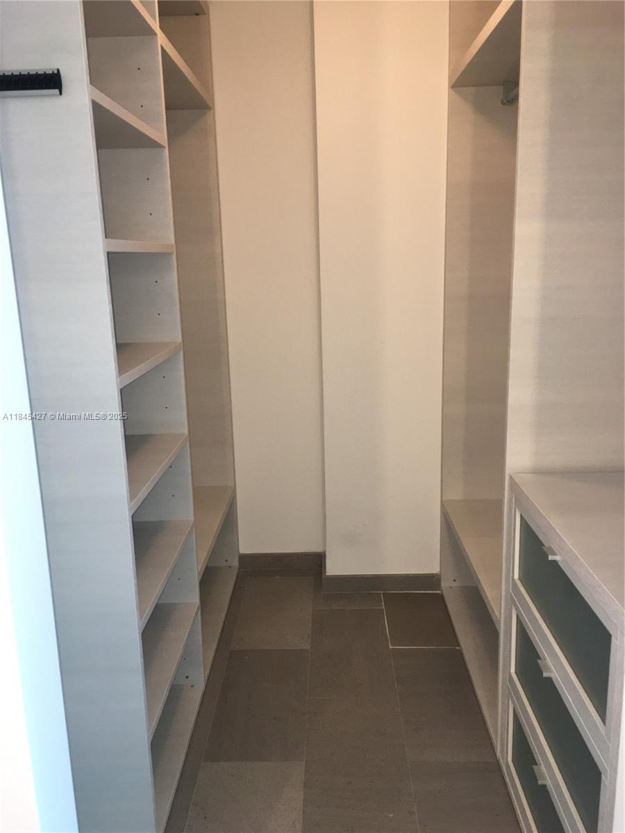 A walk-in closet features white shelving, a built-in drawer unit, and gray tile flooring — 88 SW 7th St # 2305, Miami FL 33130, MIAMI, FL