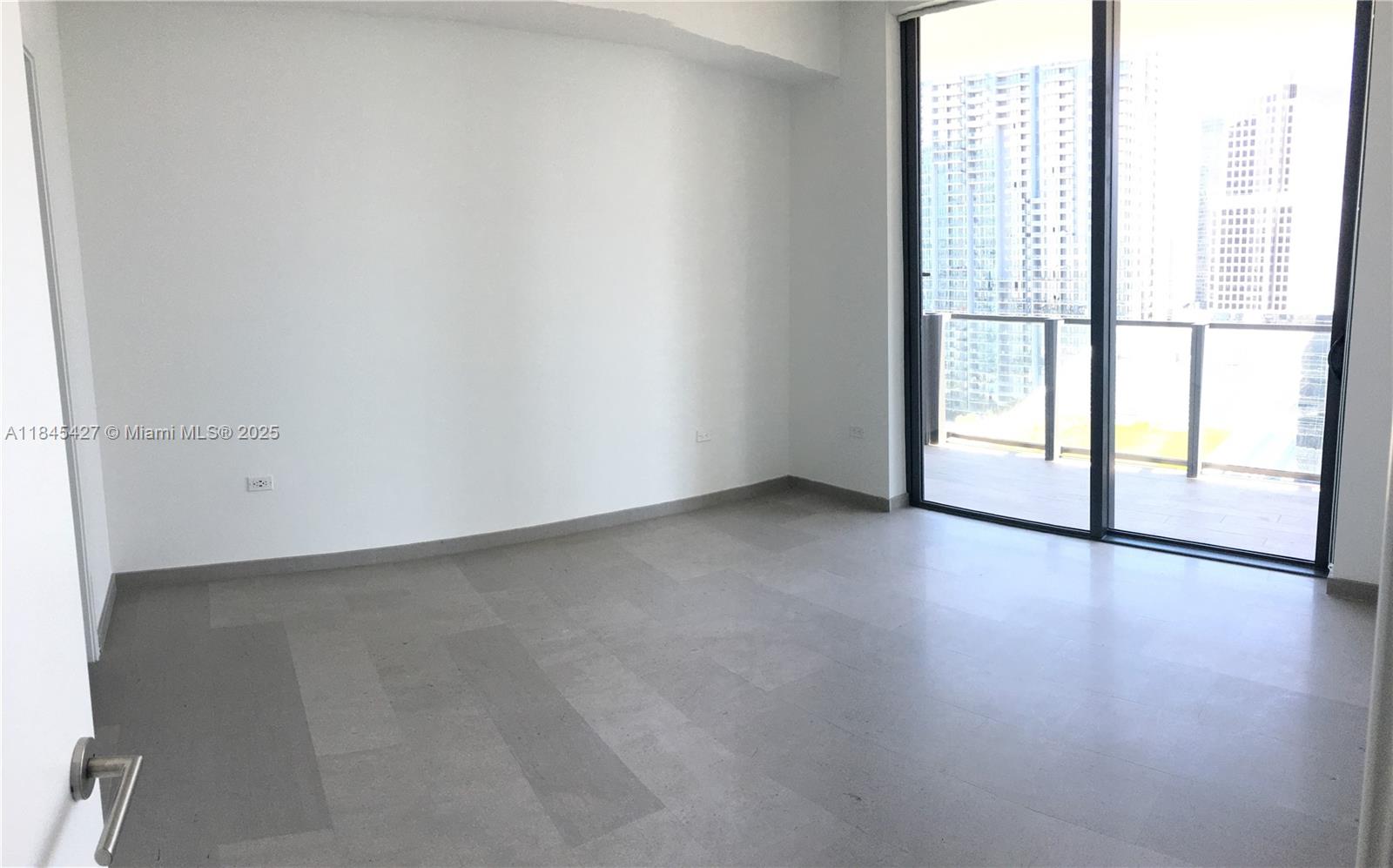 An empty room features gray tile flooring, white walls, and a sliding glass balcony door — 88 SW 7th St # 2305, Miami FL 33130, MIAMI, FL