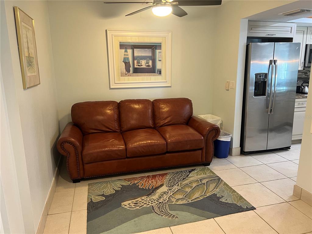 A brown leather sofa sits on a turtle-patterned rug in a room with tile floors — 1001 POINT OF ROCKS ROAD UNIT 212, SARASOTA, FL