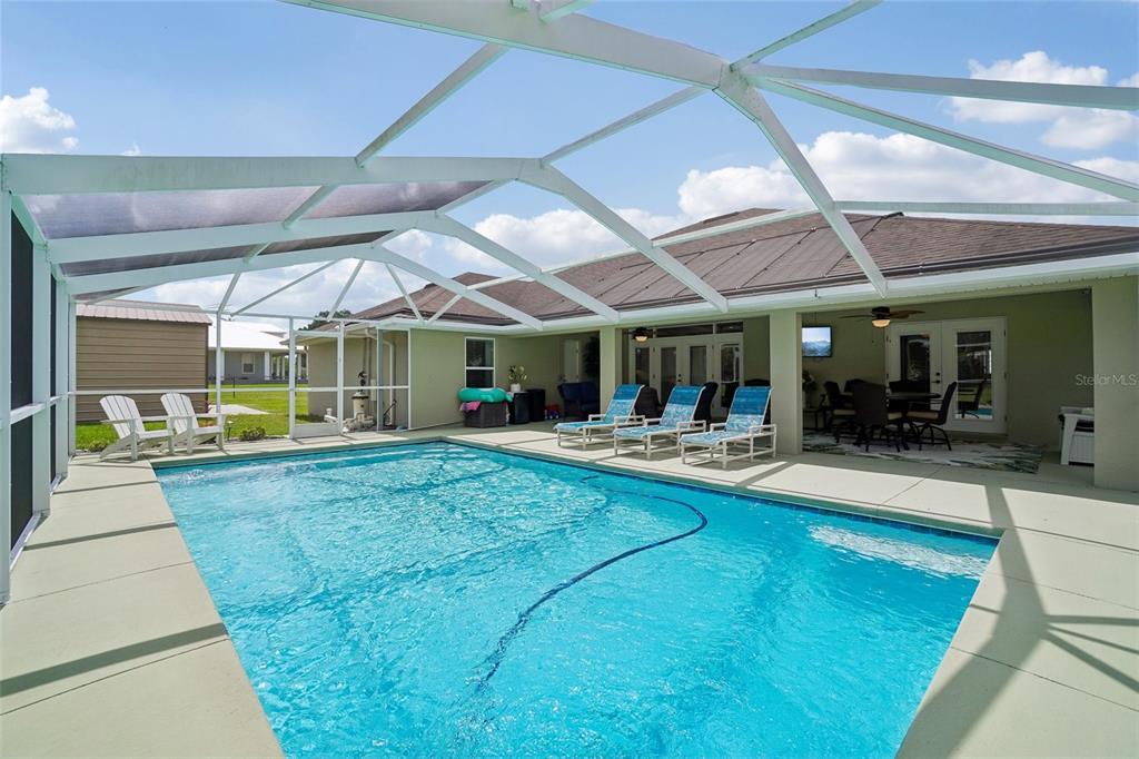 A screened-in swimming pool patio features lounge chairs, a dining area, and a covered porch — 3934 CONNERSVILLE ROAD, BARTOW, FL