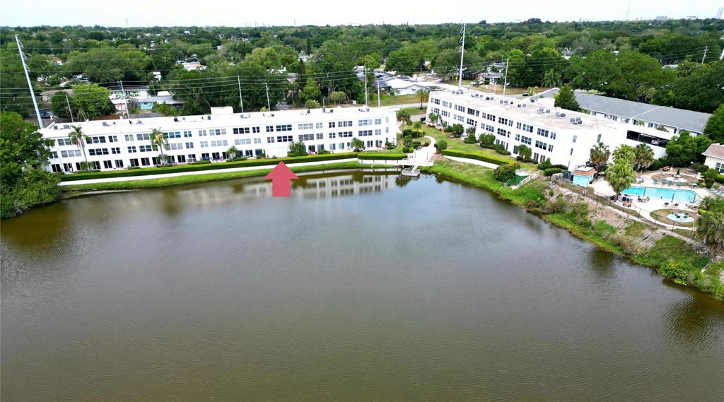 An aerial view shows two multi-story apartment buildings situated along the edge of a lake — 1655 S HIGHLAND AVENUE UNIT J190, CLEARWATER, FL