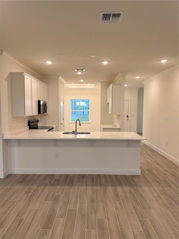 A kitchen with white cabinets, a breakfast bar, and light wood-look tile flooring — 13412 BREWSTER ROAD, SPRING HILL, FL