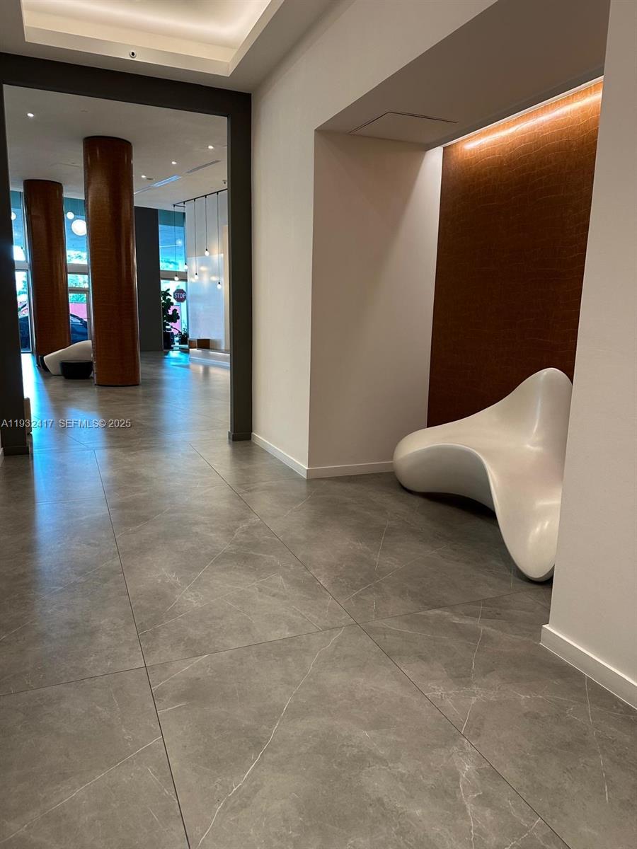 A modern lobby features large gray floor tiles, a sculptural white bench, and wood-paneled accents — 350 S Miami Ave # 2913, Miami FL 33130, MIAMI, FL