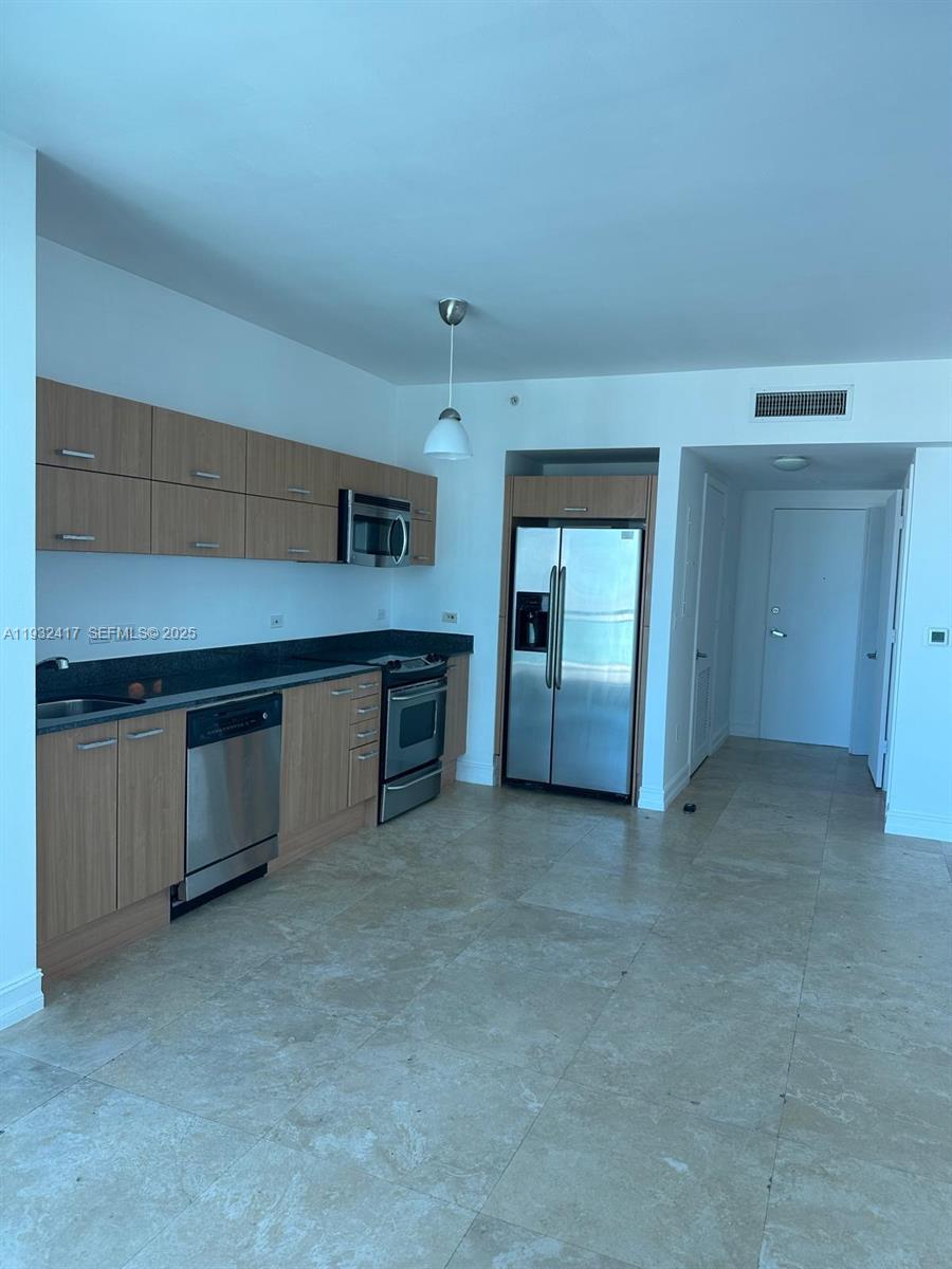 A kitchen features light wood cabinets, stainless steel appliances, and light-colored tile flooring — 350 S Miami Ave # 2913, Miami FL 33130, MIAMI, FL