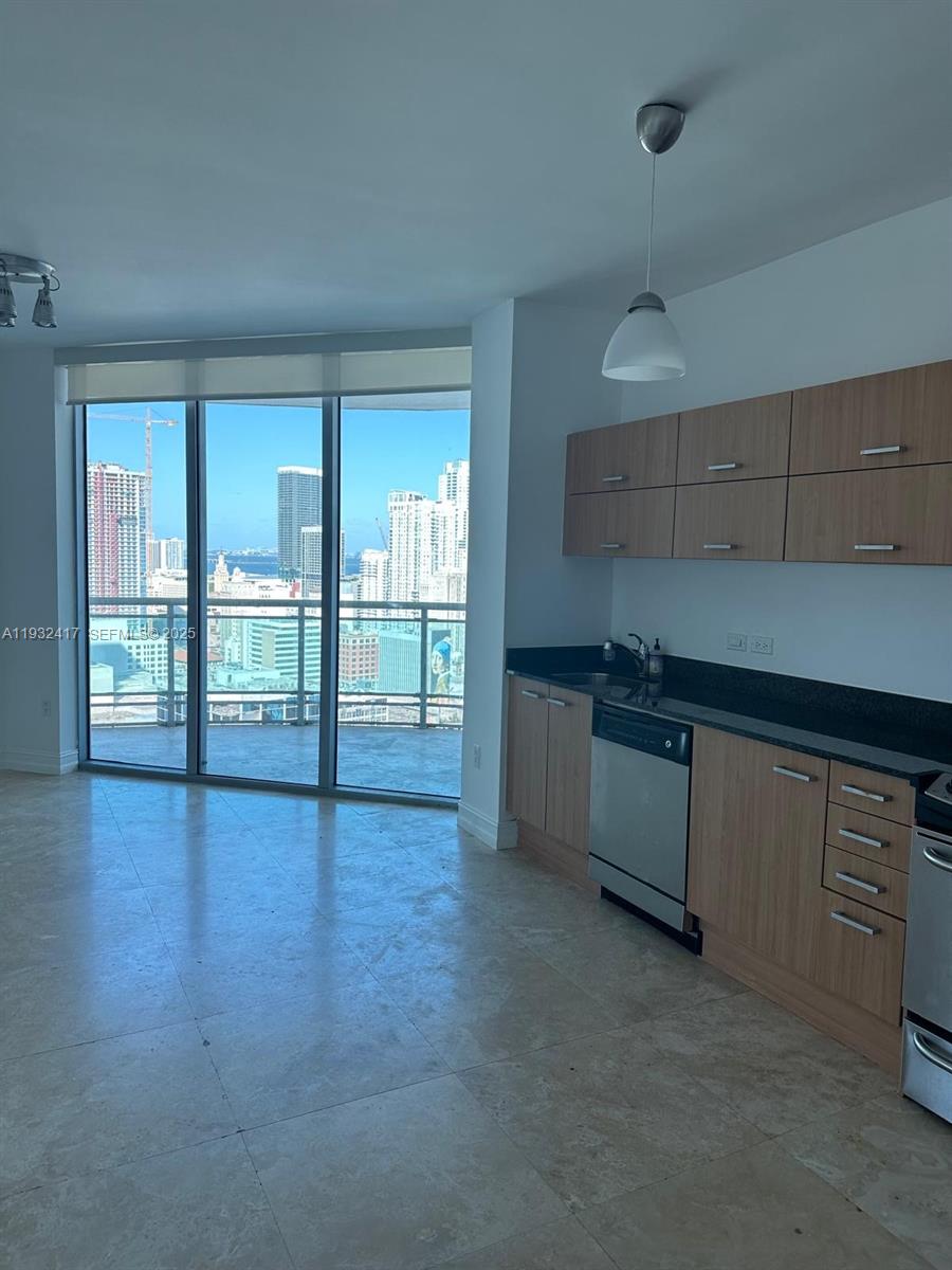 A kitchen with wood cabinets and stainless steel appliances overlooks a city skyline and water — 350 S Miami Ave # 2913, Miami FL 33130, MIAMI, FL