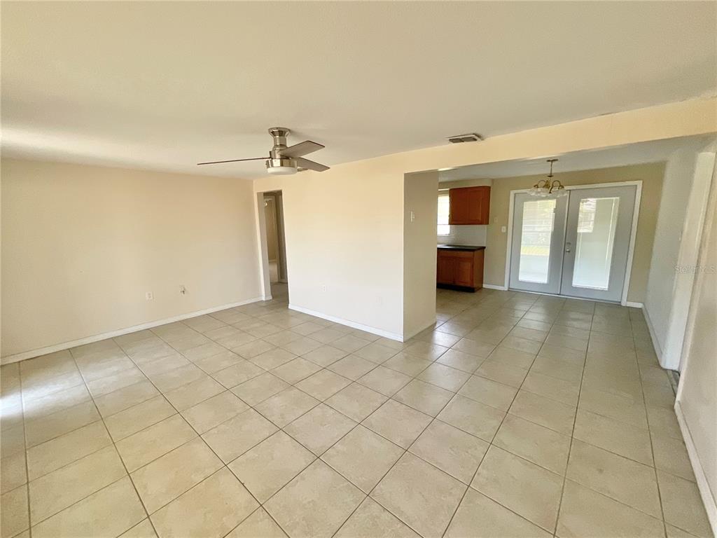 An open-concept living and dining area features light-colored tile flooring and a ceiling fan — 3528 LATIMER STREET, NEW PORT RICHEY, FL