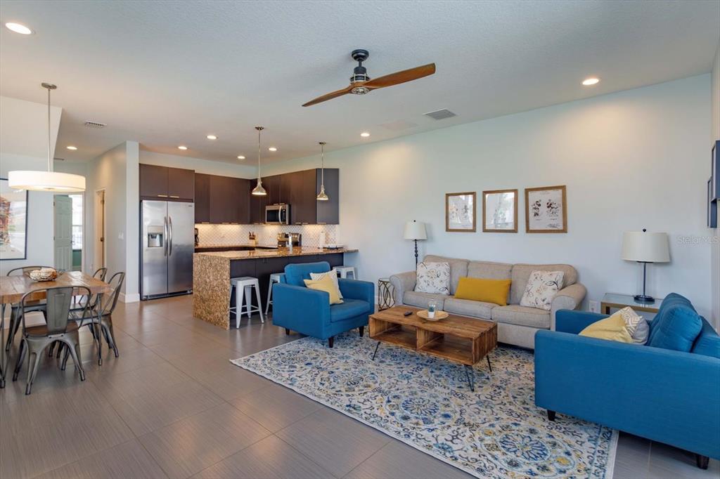 An open-concept living and dining area features a kitchen with dark cabinets and granite countertops — 1510 TRANQUIL AVENUE, CLERMONT, FL