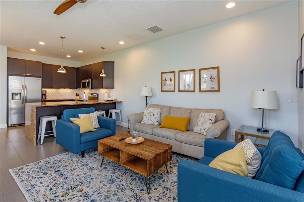 A living room with two blue armchairs, a beige sofa, and an open kitchen — 1510 TRANQUIL AVENUE, CLERMONT, FL