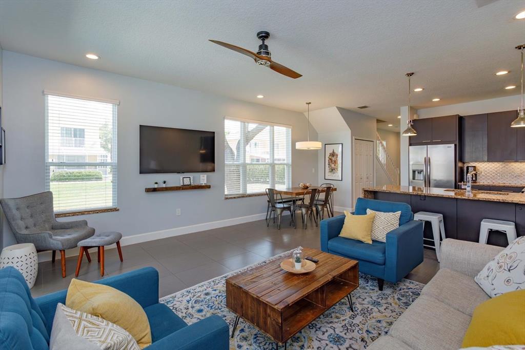 An open-concept living and dining area features tile flooring, blue armchairs, and a kitchen island — 1510 TRANQUIL AVENUE, CLERMONT, FL