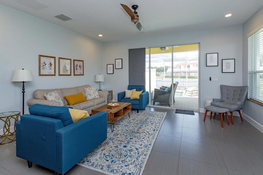 A living room features a blue sofa, a beige sofa, and a sliding glass door — 1510 TRANQUIL AVENUE, CLERMONT, FL