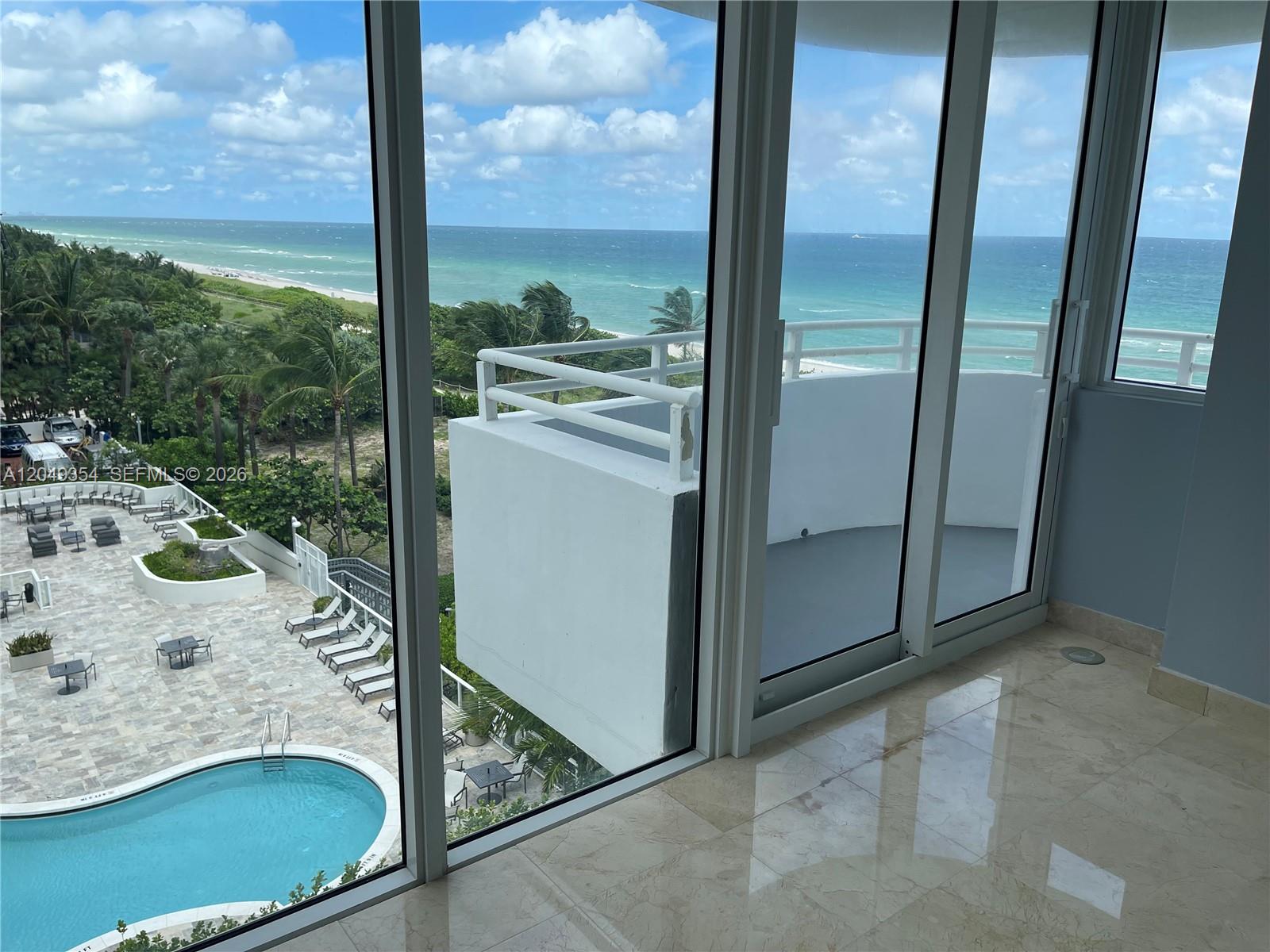 A room with marble floors overlooks a swimming pool, a balcony, and the ocean — 8911 Collins Ave # 505, Surfside FL 33154, SURFSIDE, FL