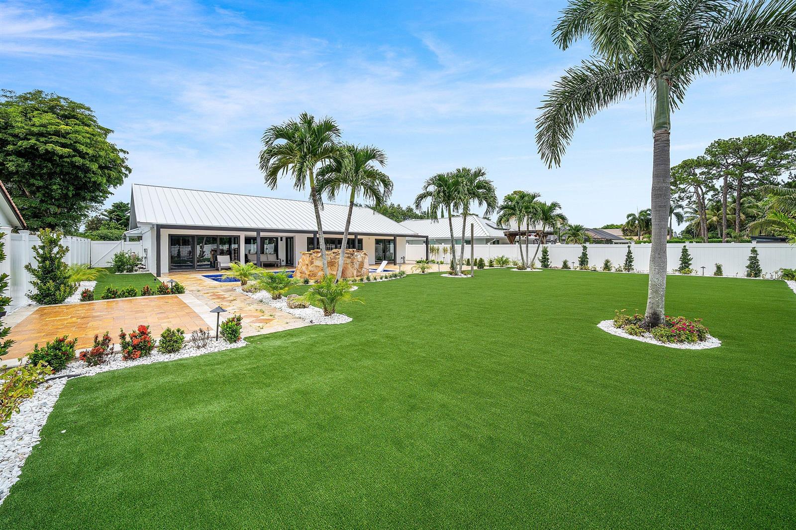 A wide backyard features artificial turf, a stone water feature, and several palm trees — 1520 SW 17th Street, Boca Raton FL 33486, BOCA RATON, FL