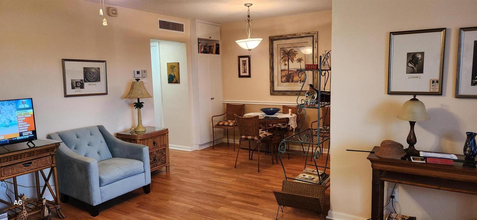 A living and dining area with light wood floors, a blue armchair, and framed artwork — 15 SE 13th Street # D3, Boca Raton FL 33432, BOCA RATON, FL