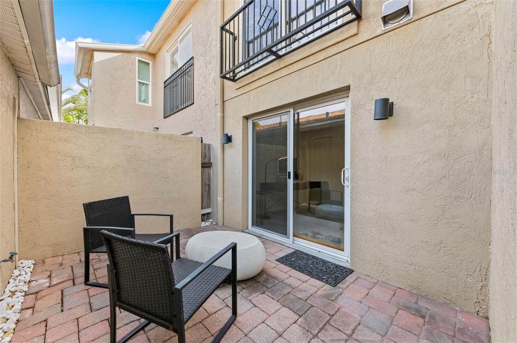 A small paved patio features two black chairs, a round white table, and sliding glass doors — 105 E DAVIS BOULEVARD UNIT B, TAMPA, FL