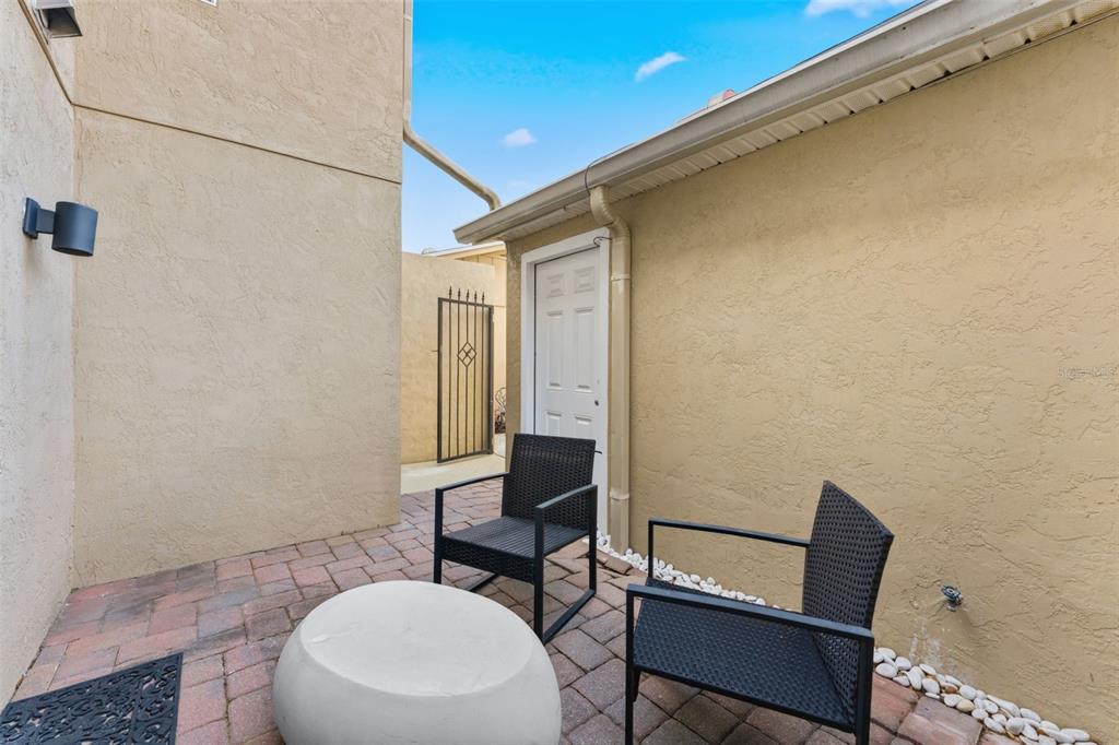 A small paved patio area features two black chairs, a round table, and stucco walls — 105 E DAVIS BOULEVARD UNIT B, TAMPA, FL