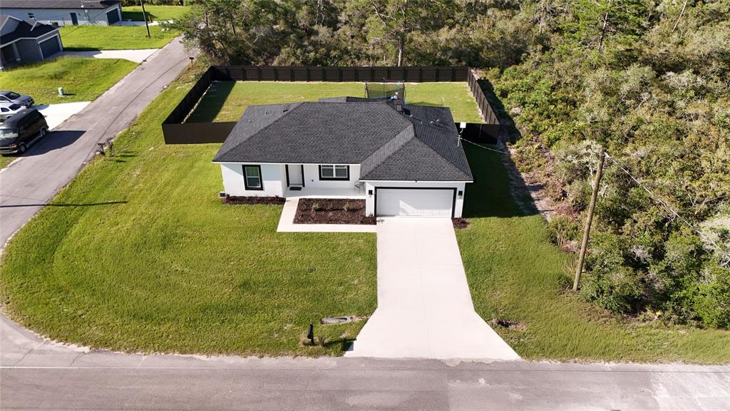 An aerial view shows a white single-story house with a black roof and fenced yard — 14 FISHER PLACE, OCKLAWAHA, FL