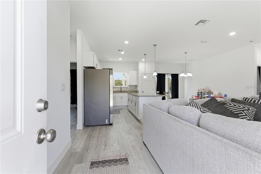 A view from a doorway into an open-concept kitchen and living area with light flooring — 14 FISHER PLACE, OCKLAWAHA, FL