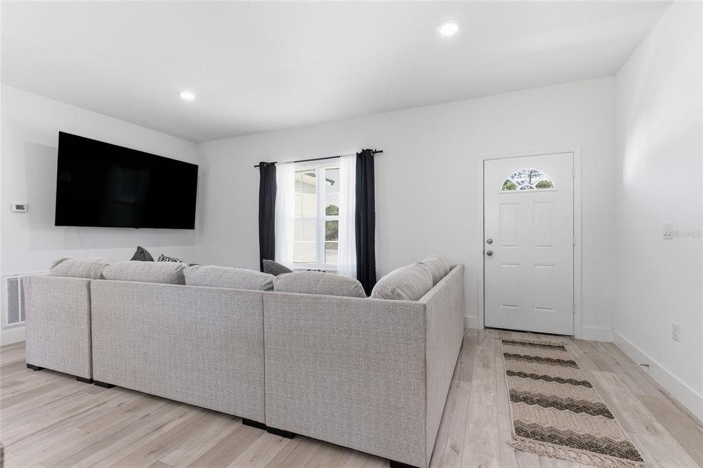 A living room features a large sectional sofa, a wall-mounted television, and a front door — 14 FISHER PLACE, OCKLAWAHA, FL