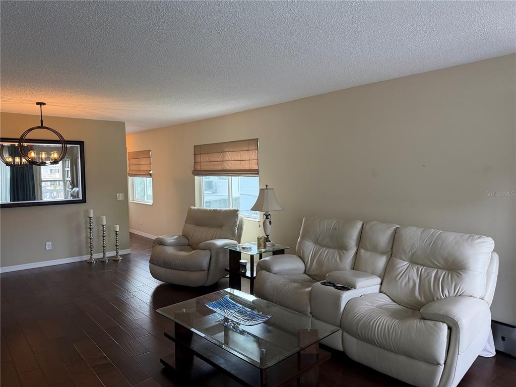 A living room features white leather seating, a glass coffee table, and dark wood flooring — 2426 ECUADORIAN WAY UNIT 40, CLEARWATER, FL