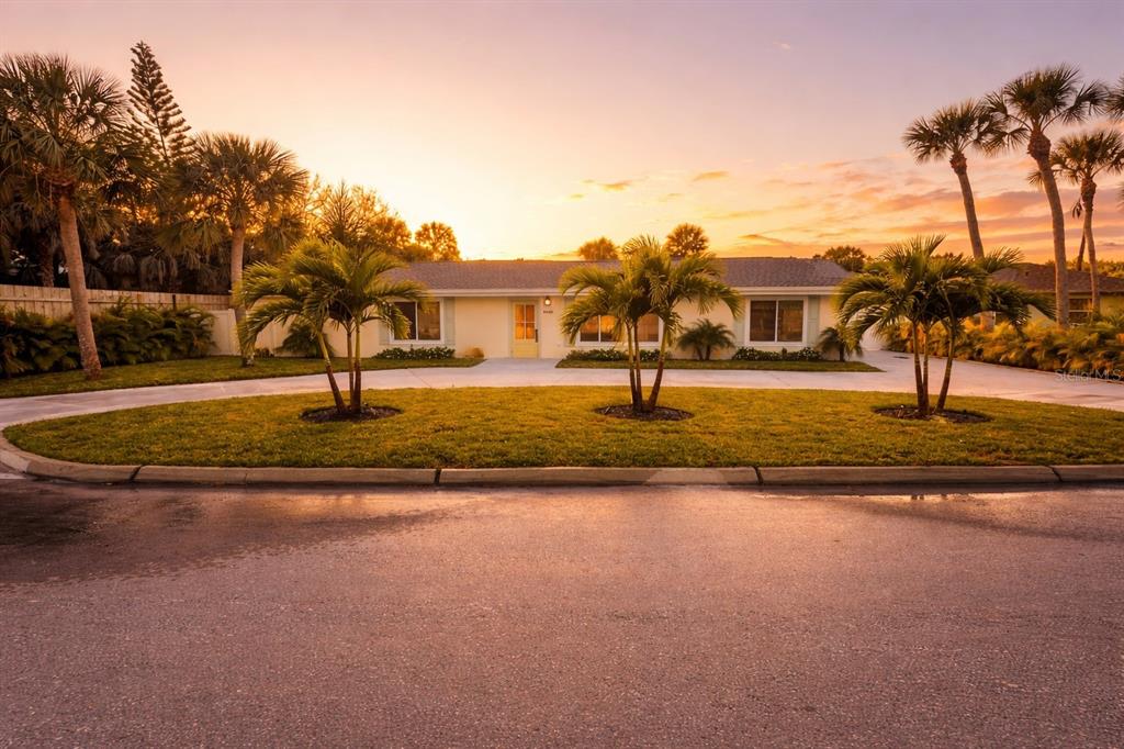 A single-story house with a circular driveway and palm trees at sunset — 4646 GLEASON AVENUE, SARASOTA, FL