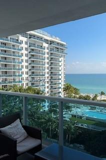 A balcony view overlooking a high-rise apartment building, a swimming pool, and the ocean — 2301 Collins Ave # 1025, Miami Beach FL 33139, MIAMI BEACH, FL