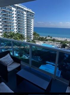 A balcony view overlooks a swimming pool, a high-rise building, and the ocean — 2301 Collins Ave # 1025, Miami Beach FL 33139, MIAMI BEACH, FL